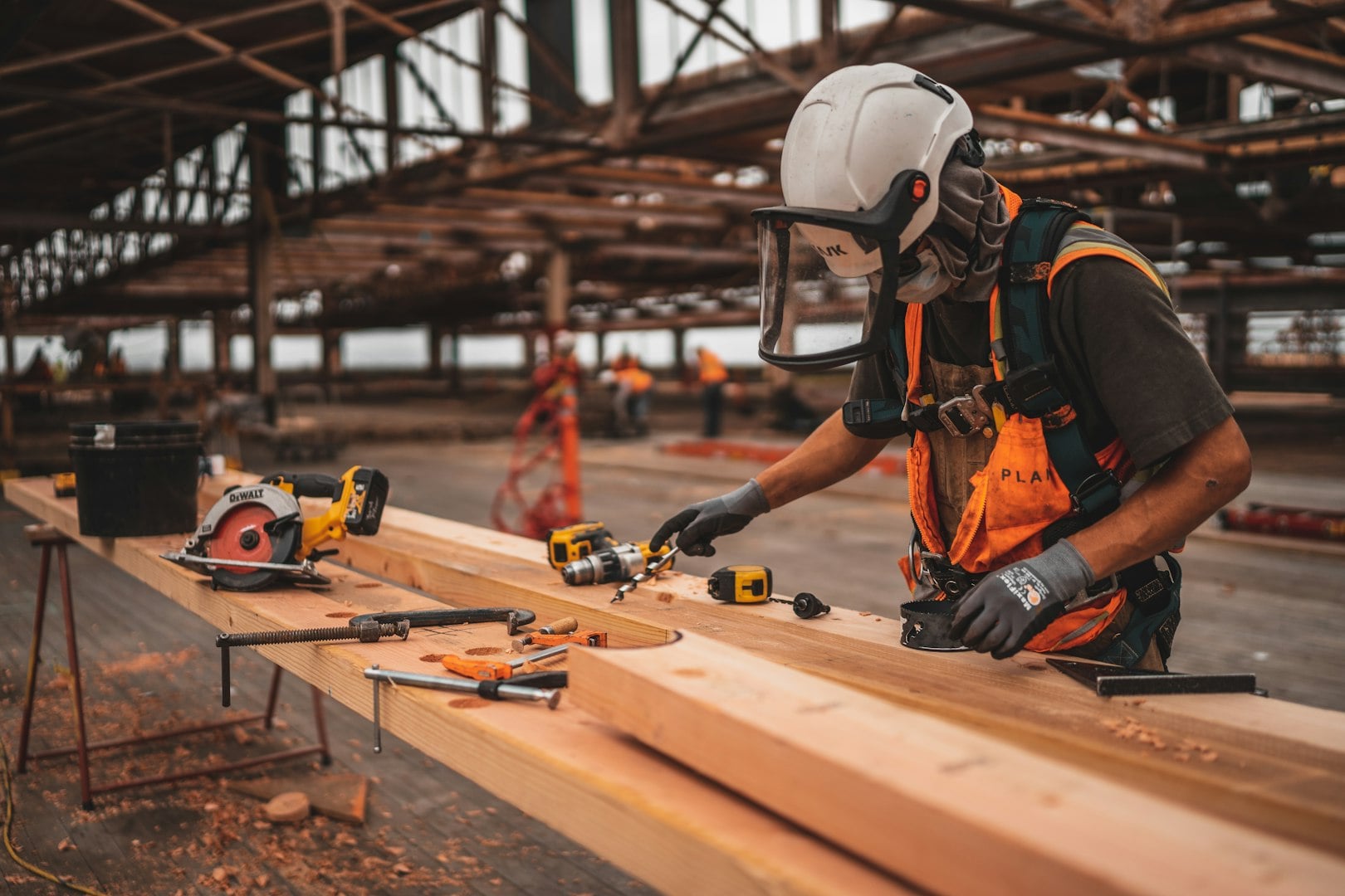 Building contractor cooperating with a worker and project manager while analyzing construction plans at building site.